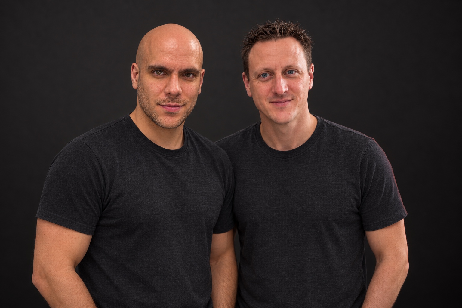 Vincent on the left and Mitchell on the right, wearing black shirts against a charcoal studio background.